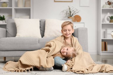 Küçük bir çocuk ve kız kardeşi evde ekoseyle uyuyorlar.