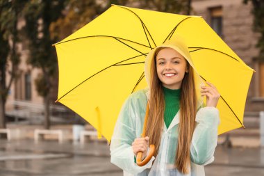 Yağmurlu bir günde yağmurluk giymiş güzel, mutlu bir kadın.