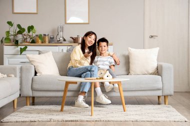 Genç anne ve küçük oğlu evde televizyon seyrediyor.