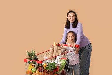 Güzel, genç, mutlu anne ve kızı bej arka planda alışveriş arabalarıyla