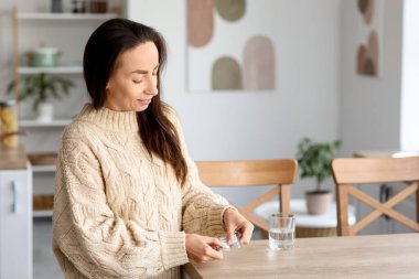 Güzel bir kadın mutfakta ilaç alıyor.