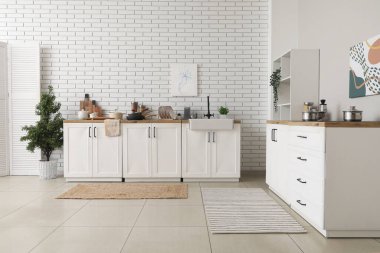 Mutfak tezgahında beyaz tuğla duvarın yanında.