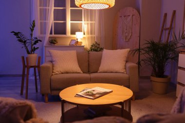 Geceleri kanepe, masa ve parlayan lambayla oturma odasının içinde.