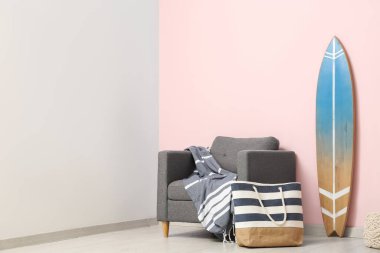 Gri koltuklu, el çantalı ve sörf tahtalı şık bir oturma odası.