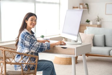 Ofiste boş bilgisayarla çalışan genç bir kadın.