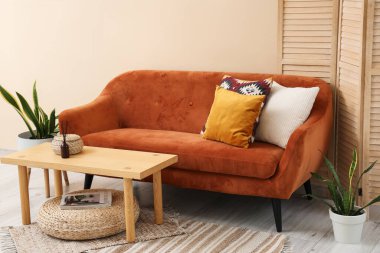 Rahat kahverengi kanepe ve oturma odasındaki bej duvarın yanındaki masa, yakın çekim.