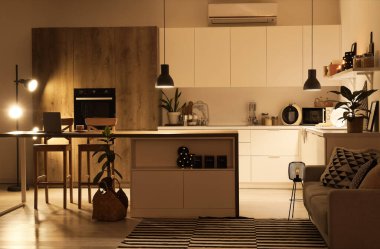 Geceleri tezgahları, masa lambaları ve parlayan lambaları olan modern mutfağın içi.