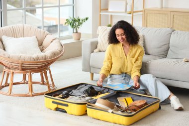 Genç Afro-Amerikalı bir kadın haritayla eve gitmek için bavul hazırlıyor.