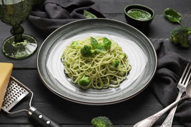 Siyah ahşap zemin üzerinde brokoli ve fesleğen yapraklı lezzetli spagetti makarna tabağı