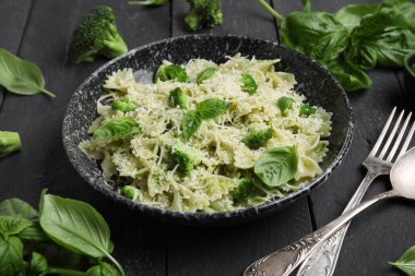 Brokoli ve fesleğen yapraklı bir kase lezzetli farfalle makarna. Siyah ahşap arka planda, yakın plan.