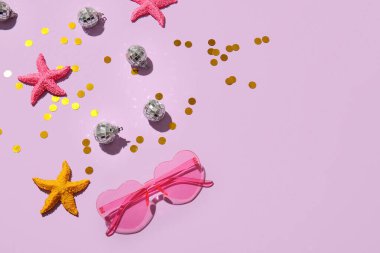 Şık güneş gözlüklü kompozisyon, renkli deniz yıldızları ve arka planda küçük disko topları