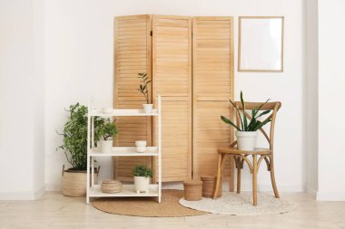 Raflar, sandalye, ev bitkileri ve ahşap perdeli şık bir oda.