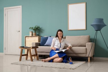 İşten sonra evde dinlenirken dergi okuyan genç bir kadın.