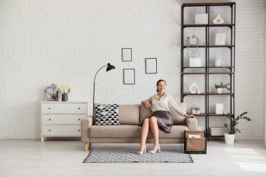 İşten sonra evdeki kanepede dinlenen genç bir kadın.