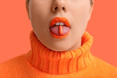 Turuncu rujlu ve arka planda haplı kadın, yakın plan.