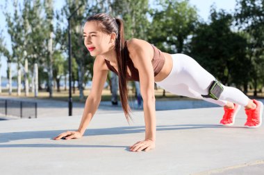 Sportif genç bir kadın açık havada kalas yapıyor.