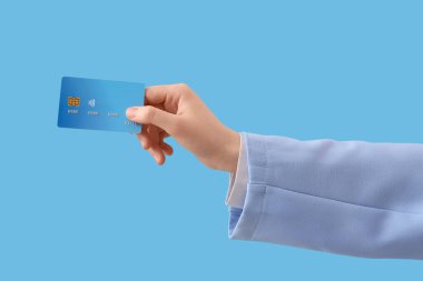 Mavi arka planda kredi kartı olan bir kadın.