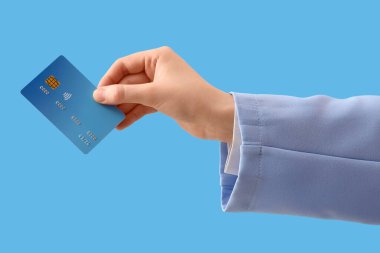 Mavi arka planda kredi kartı olan bir kadın.