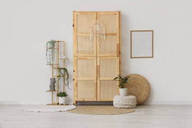 Odanın içinde ahşap dolap, puf ve bitkiler var.