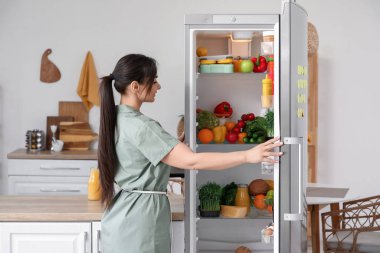 Mutfakta buzdolabını açan güzel bir kadın.