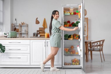 Mutfakta buzdolabını açan güzel bir kadın.