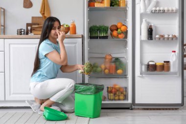 Mutfaktaki buzdolabından bozuk yemek atan güzel bir kadın.