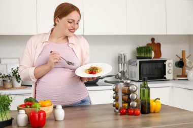 Mutfakta spagettisi olan hamile bir kadın.