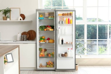 Mutfağın iç tarafındaki pencerenin yanındaki ürünlerle birlikte buzdolabını aç