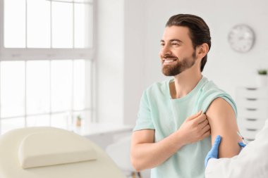 Genç adam klinikteki doktordan aşı alıyor.