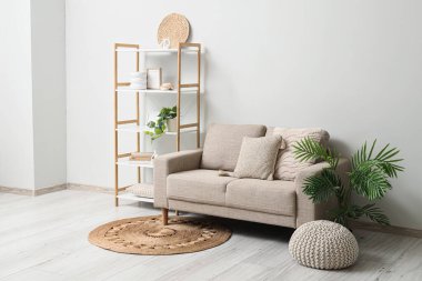 Oturma odasının içinde kanepe, raf ünitesi ve hasır halı var.