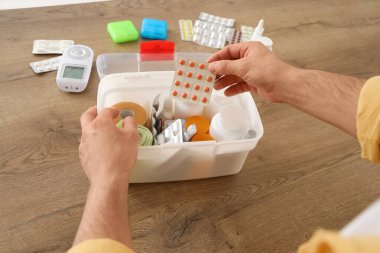 Erkek eller mutfaktaki masada ilk yardım çantasından hap alıyor.