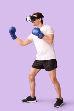 Eflatun arka planda boks eldivenli, VR gözlüklü genç bir adam.
