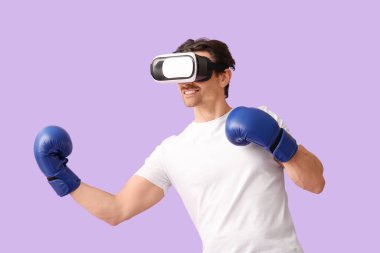 Eflatun arka planda boks eldivenli, VR gözlüklü genç bir adam.
