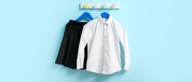 Mavi duvarda asılı şık okul üniforması.