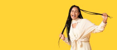 Sarı arka planda örgülü saçları olan mutlu Afro-Amerikalı kadın ve mesaj için yeri var.