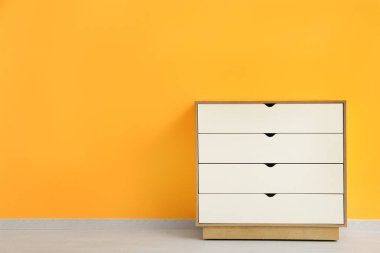 Turuncu duvarın yanındaki açık tahta çekmeceler.