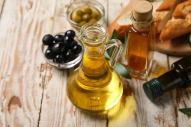 Beyaz ahşap arka planda taze zeytinyağlı sürahi.