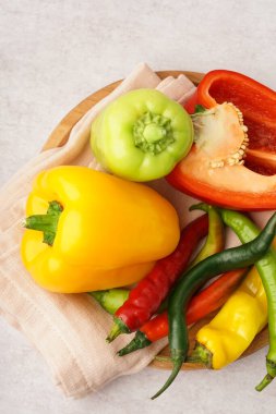 Beyaz arka planda farklı taze biberli ahşap tabak.