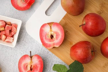Board and bowl with sweet pink apples on white background