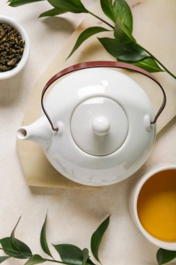 Fincanlı çaydanlık, bir kase kuru çay ve beyaz grunge arka planda yapraklar.