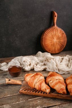 Lezzetli kruvasanlar ve ahşap masada bir kase reçel.