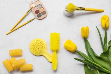 Beyaz arka planda saç fırçaları, lale çiçekleri ve makyaj ürünleri
