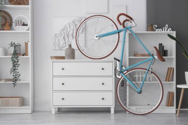 Çekmeceleri, raf üniteleri, bisikleti ve saksısı olan ışık odasının içinde.