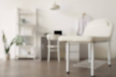 Kanepesi, doktor çalışma yeri ve raf ünitesi olan bulanık tıbbi ofis manzarası.