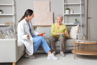 Evde masaj topları olan yaşlı bir kadın ve fizyoterapist.