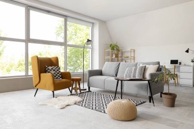 Gri kanepeli, masalı ve koltuklu aydınlık oturma odasının içi.