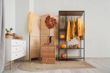 Giysi askısı, balkabağı ve katlama perdesi olan soyunma odasının içinde.