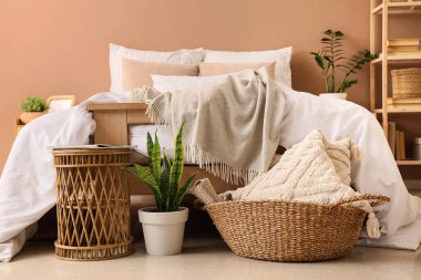 Büyük yataklı, sepetli, sepetli, kahve masalı ve çiçekli modern yatak odasının içi.