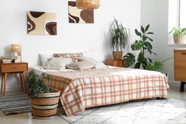 Yatak odasının içinde rahat yatak ve bitkiler var.