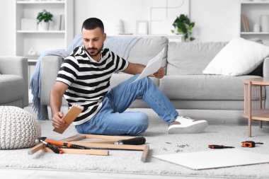 Talimatları evde toplayan genç adam.